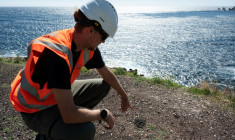 Un agent montre les dépôts de scories lors d'une visite de presse pour montrer l'avancement des travaux de dépollution aux "Goudes", un quartier et port du 8e arrondissement de Marseille, la porte sud de la ville et du Parc National des Calanques, le 11 septembre 2025 ( AFP / Miguel MEDINA )