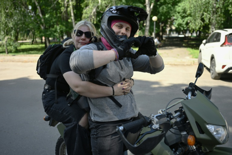 Arina, sur le point de rejoindre l’armée, enlace sa compagne, Anna, militaire, dans un endroit non divulgué, en Ukraine, le 7 juin 2026 ( AFP / Genya SAVILOV )