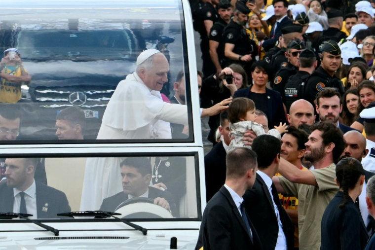 Le pape Leon XIV bénit un enfant lors de sa descente des Champs-Elysées en papamobile, avant de célébrer une messe géante place de la Concorde à Paris, le 26 septembre 2026 ( AFP / Alberto PIZZOLI )