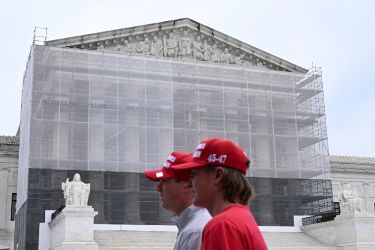 Deux hommes portant des casquettes "Make America Great Again" (MAGA, Rendre sa grandeur à l'Amérique), passent devant la Cour suprême des Etats-Unis, à Washington, le 27 juin 2025 ( AFP / Alex WROBLEWSKI )