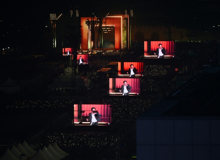 Des fans de BTS regardent le concert marquant le retour du groupe de K-pop sur des écrans installés à Séoul, le 21 mars 2026 ( AFP / Jung Yeon-je )