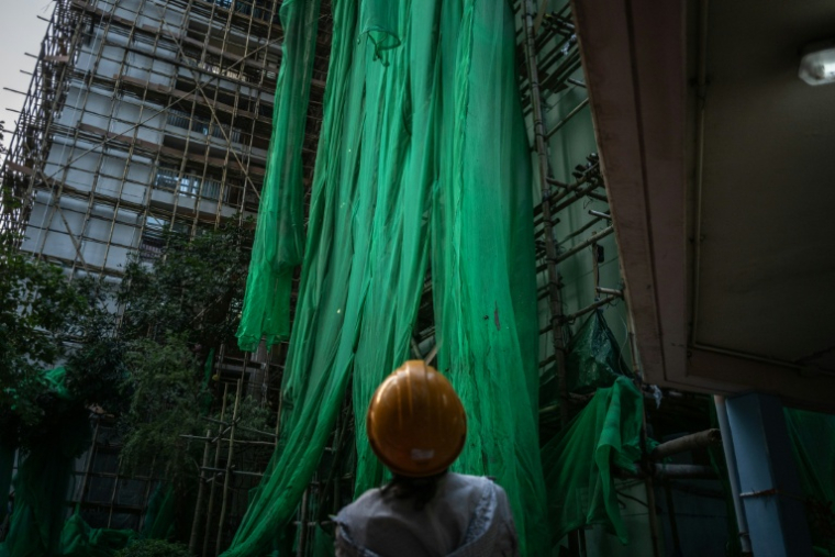 Un ouvrier enlève les filets de protection sur un immeuble en chantier à Hong Kong, en Chine, le 4 décembre 2025 ( AFP / Philip FONG )