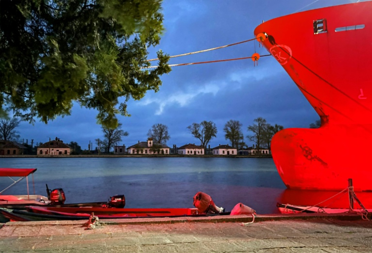 Un navire à l'ancre est illuminé par une lumière rouge utilisée pendant la nuit pour la navigation, à Sulina, le 9 mai 2026, en Roumanie ( AFP / Daniel MIHAILESCU )