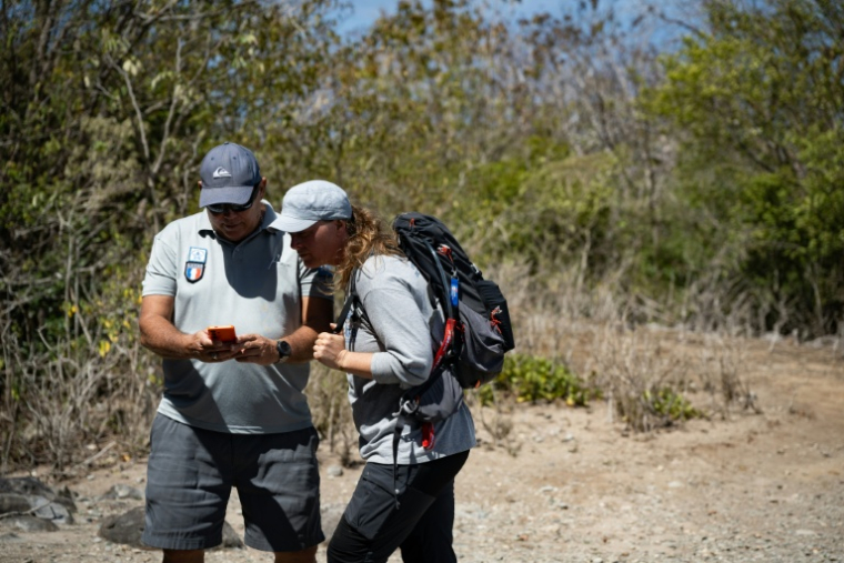 Philippe de Proft (G), garde-littoral, et Marie Robert, de l'Office français de la biodiversité, examinent un serpent sur la colline du Chameau à Terre-de-Haut, aux Saintes, le 18 mars 2026 en Guadeloupe ( AFP / Carla Bernhardt )