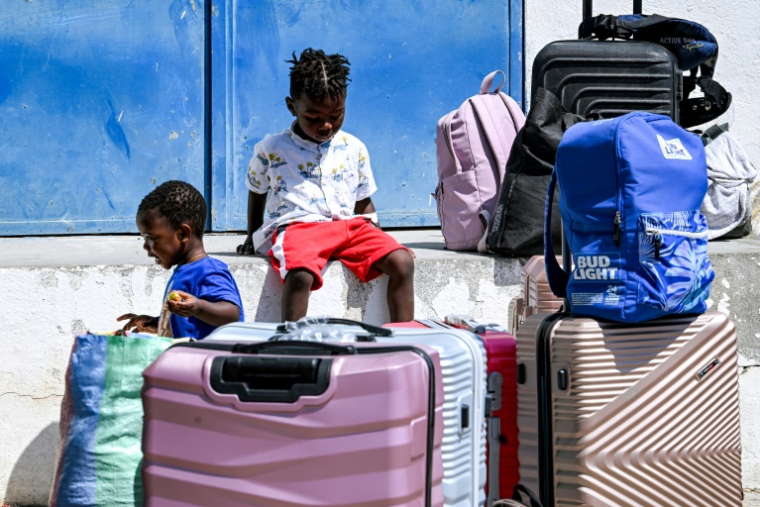 Des enfants de migrants subsahariens attendent près de valises avant leur retour par vol dans leur pays d'origine, le 16 juin 2026 à Tunis ( AFP / FETHI BELAID )