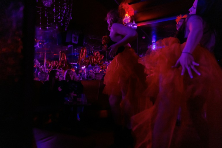 La manager Valérya Zavatska (g), diplômée en droit, et sa mère, ancienne danseuse, regardent les danseuses lors d'une représentation au club de strip-tease "Flash Dancers", le 15 mai 2025 à Kharkiv, en Ukraine ( AFP / Tetiana DZHAFAROVA )
