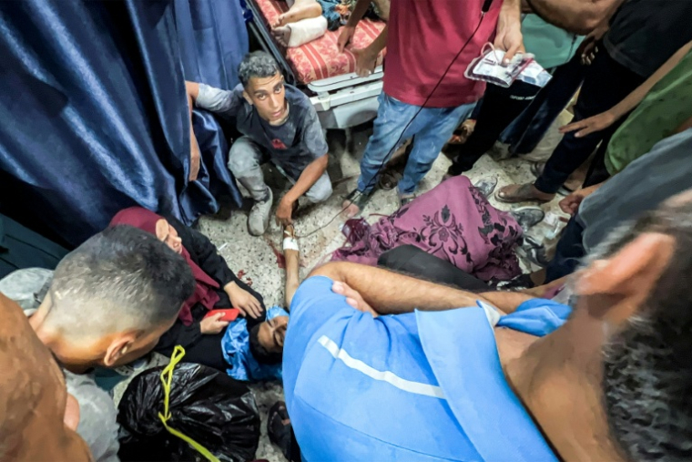 Des Palestiniens entourent l'une des personnes blessées en attendant de l'aide humanitaire près du point de passage de Zikim, dans le nord de la bande de Gaza, le 30 juillet 2025 ( AFP / Bashar TALEB )