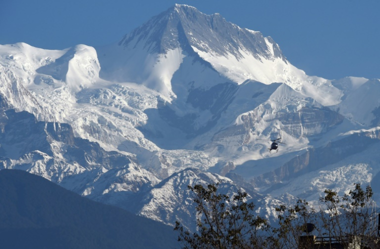 Un hélicoptère survole la chaîne de montagnes de l'Annapurna, le 22 janvier 2020 ( AFP / PRAKASH MATHEMA )