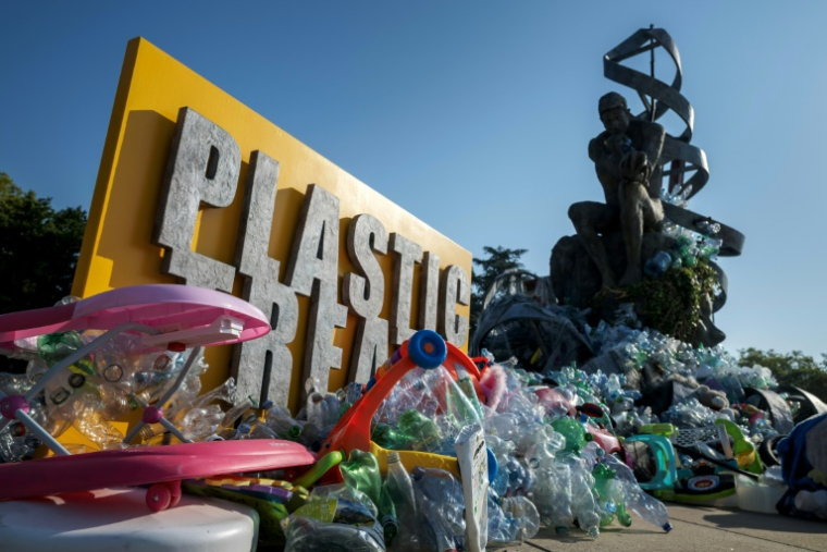 Le "Fardeau du Penseur", une installation évolutive de l'artiste, photographe et militant canadien Benjamin Von Wong devant le siège genevois de l'Onu, est peu à peu recouvert de déchets plastique, alors que les délégués réunis à l'intérieur du Palais des Nations ont bien du mal à trouver un terrain d'entente pour rédiger le premier traité international sur la pollution plastique, le 12 aout 2025 ( AFP / Fabrice COFFRINI )