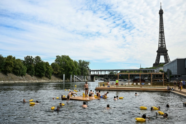 Des baigneurs nagent dans la Seine sur un site aménagé sur le bras de Seine de Grenelle, près de la tour Eiffel (en arrière-plan), à Paris, le 5 juillet 2025 ( AFP / JULIEN DE ROSA )