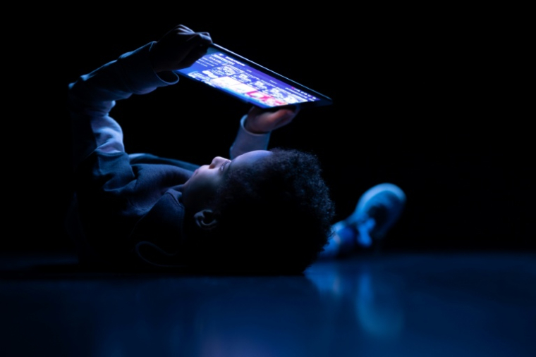 Un enfant regarde une tablette à Paris, le 14 février 2024. ( AFP / JOEL SAGET )