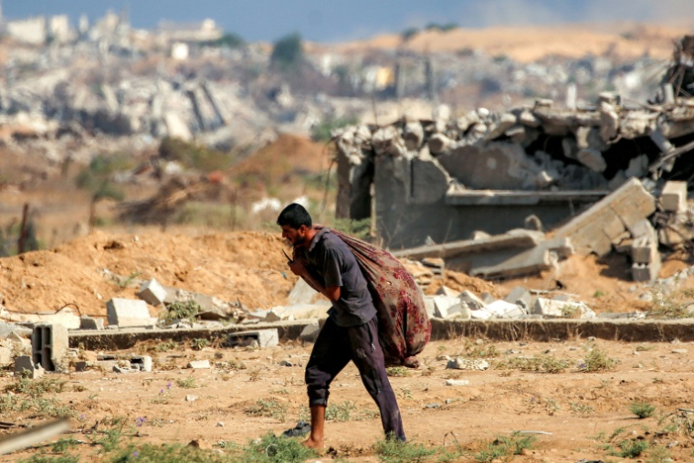 Un homme porte un sac d'aide humanitaire,  à Nousseirat, dans le centre de la bande de Gaza, le 30 septembre 2025 ( AFP / Eyad BABA )