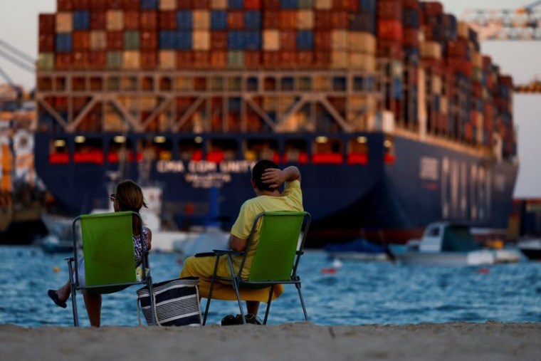Des personnes se détendent devant un porte-conteneurs CMA CGM