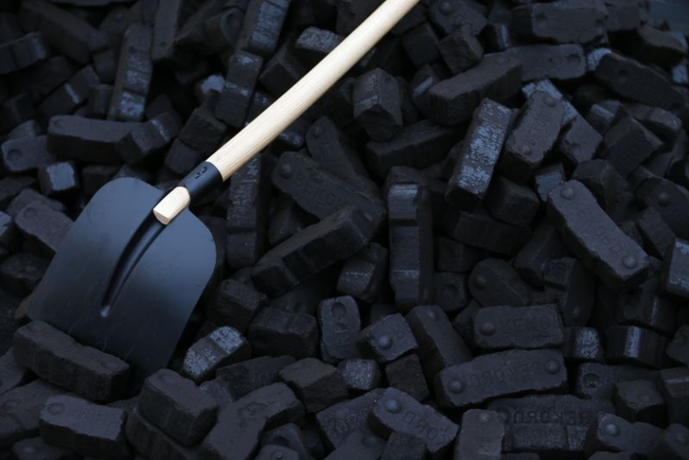 Une pelle est placée sur des briquettes de charbon