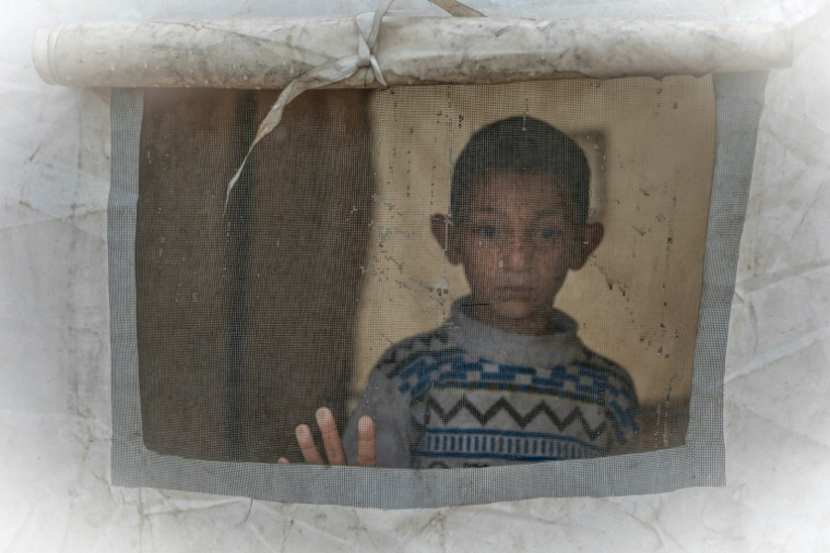 Un jeune Gazaoui regarde depuis l'ouverture d'une tente après de fortes pluies dans un camp de déplacés palestiniens, dans le quartier de Zeitoun de la ville de Gaza, le 11 décembre 2025 ( AFP / Omar AL-QATTAA )