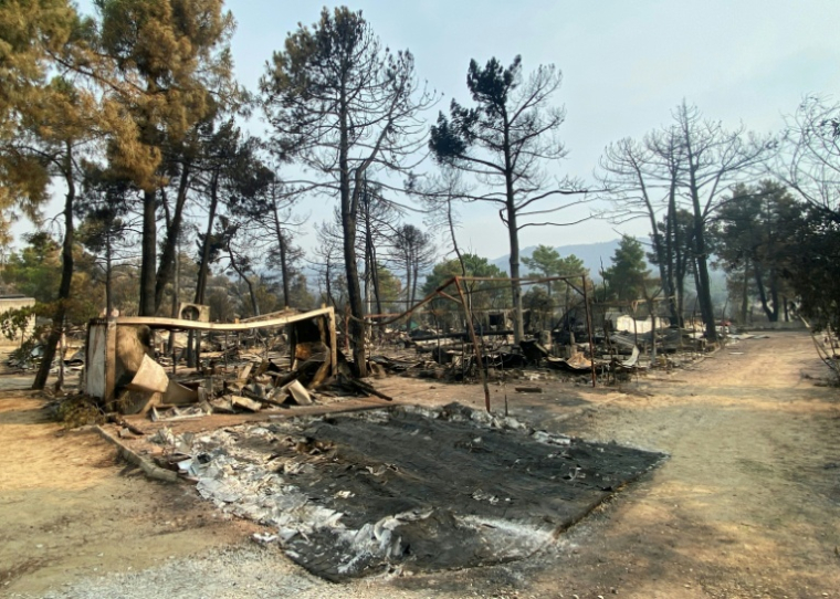 Restes calcinés de caravanes et de tentes dans un camping du Pantano de Burguillo, à El Barraco, à 100 kilomètres à l'ouest de Madrid, le 27 juillet 2026 ( AFP / Roland LLOYD PARRY )