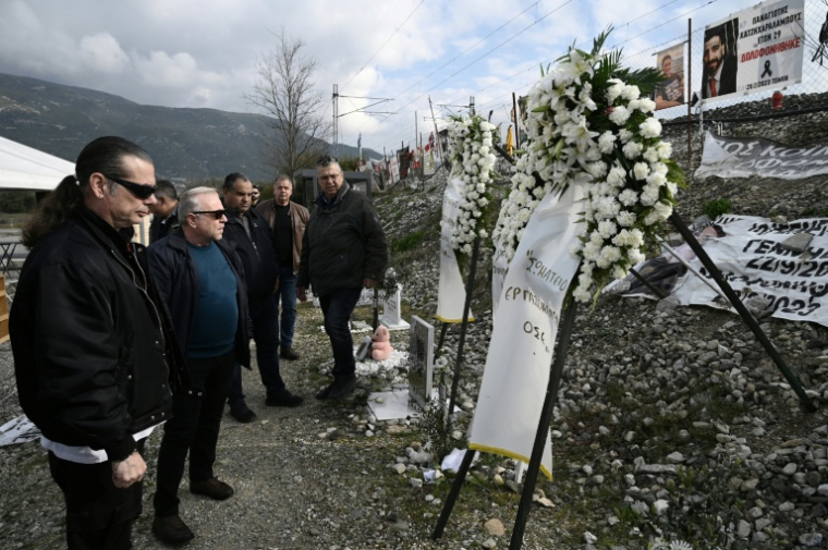 Des membres du syndicat des travailleurs de la compagnie Hellenic Train rendent hommage aux victimes de la collision de Tempi sur le site de l’accident, le 28 février 2026 ( AFP / SAKIS MITROLIDIS )