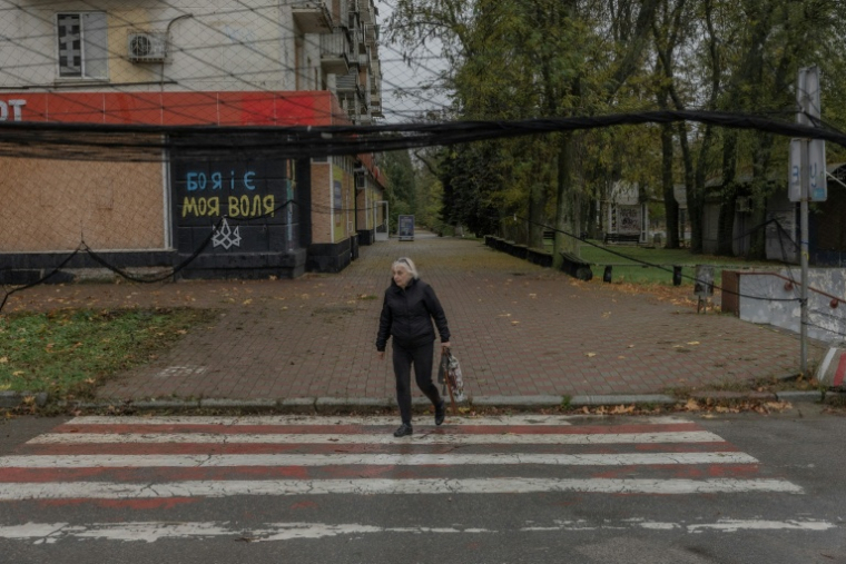 Une femme marche dans une une rue où des filets antidrones ont été disposés,  30 octobre 2026 à Kherson, dans le sud de l'Ukraine  ( AFP / Roman PILIPEY )