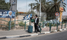 Un couple israélien à côté d'affiches de campagne du Premier ministre israélien Benjamin Netanyahu, dans la colonie israélienne d'Ofra, en Cisjordanie occupée, le 13 octobre 2026 ( AFP / Ilia YEFIMOVICH )
