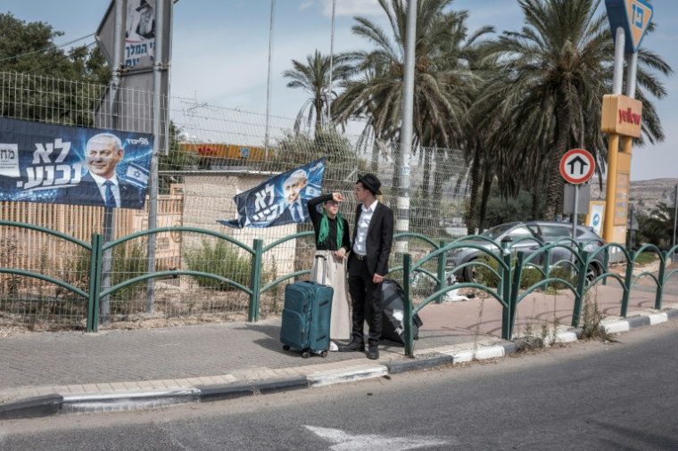 Un couple israélien à côté d'affiches de campagne du Premier ministre israélien Benjamin Netanyahu, dans la colonie israélienne d'Ofra, en Cisjordanie occupée, le 13 octobre 2026 ( AFP / Ilia YEFIMOVICH )