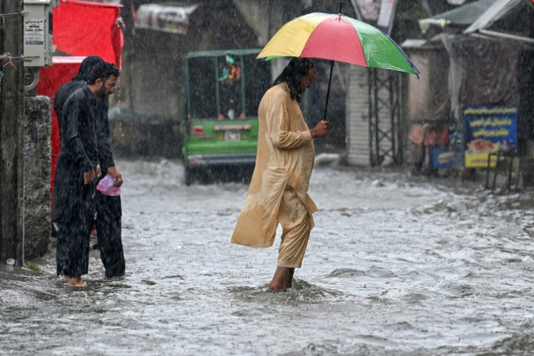 Des personnes dans une rue inondée de Rawalpindi, près d'Islamabad, le 17 juillet 2025 ( AFP / Aamir QURESHI )