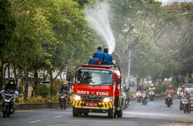 Des pompiers projettent de l'eau dans une rue pour évacuer les cendres provoquées par l'éruption du volcan Anak Krakatoa à Bandar Lampung, le 6 septembre 2026 en Indonésie ( AFP / PERDIANSYAH )