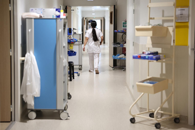 Une infirmière marche dans un couloir du service d'oncologie de l'hôpital Notre-Dame de la Miséricorde à AJaccio, le 6 mai 2025. ( AFP / PASCAL POCHARD-CASABIANCA )