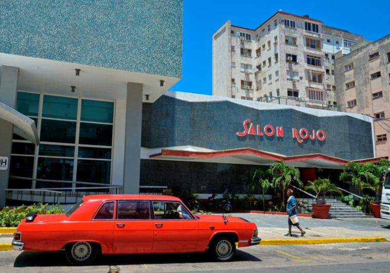 Une limousine Tchaïka soviétique des années 1970 passe devant le "Salon rouge" de l'hôtel Capri, un ancien casino fermé après la révolution castriste, à La Havane, le 14 avril 2025 ( AFP / ADALBERTO ROQUE )
