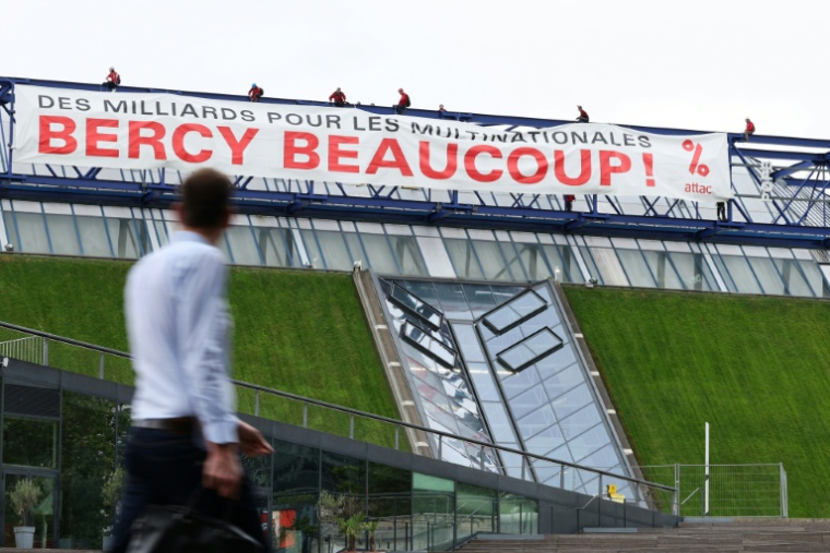 Des militants de l'organisation Attac France déploient une banderole sur la salle de spectacles Accor Arena à Paris mardi 2 juin 2026, protestant contre les aides publiques aux multinatinales  ( AFP / Kenzo TRIBOUILLARD )
