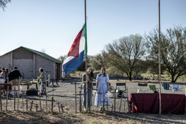 Une habitante d'Orania, Cara Tomlinson, hisse le drapeau de l'ancienne République sud-africaine au cimetière construit sur les lieux d'un camp de concentration de la guerre anglo-boer à Doornbult, près d'Orania, le 30 mai 2026. ( AFP / MARCO LONGARI )