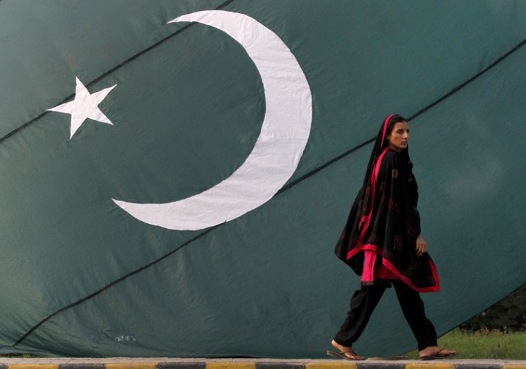 Une femme passe devant un drapeau national du Pakistan