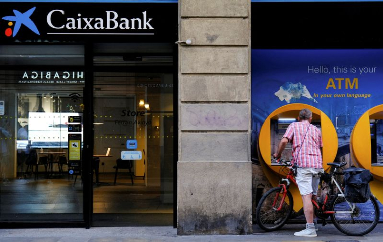 Un homme utilise un guichet automatique Caixabank à Barcelone, en Espagne