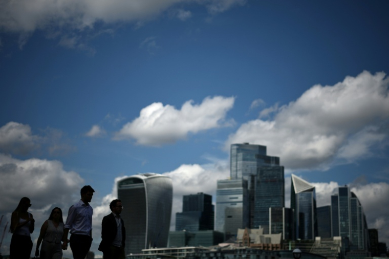 Des passants le long de la rive sud de la Tamise d'où l'on aperçoit le quartier des affaires et financier du centre de Londres, le 14 août 2025 ( AFP / HENRY NICHOLLS )
