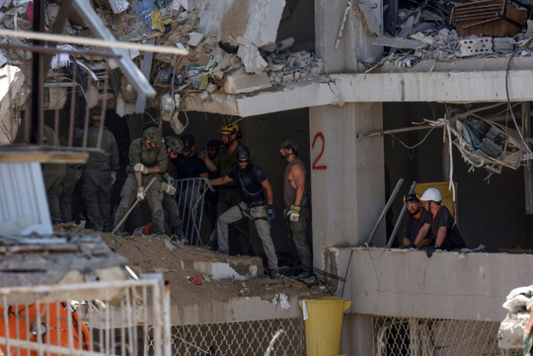 Secouristes et militaires israéliens fouillent les décombres d'un bâtiment lourdement endommagé par des tirs de missiles iraniens dans la ville côtière de Bat Yam, au sud de Tel-Aviv, le 15 juin 2025 ( AFP / GIL COHEN-MAGEN )