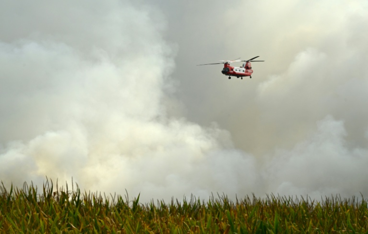 Un hélicoptère CH-47D Chinook du Service des pompiers ruraux (RFS) de Nouvelle-Galles du Sud, en Australie, survole la forêt de Luglon lors d'un incendie de forêt, dans le sud-ouest de la France, le 14 août 2026 ( AFP / Gaizka IROZ )