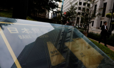 Photo d'un homme qui passe devant une pancarte de la Banque du Japon devant son siège à Tokyo
