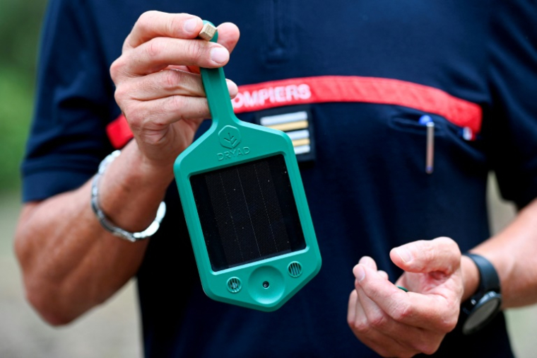 Le chef du groupement Prévisions des pompiers du Gard, Eric Guiboud-Ribaud, montre l'un des petits boîtiers, connectés par satellites et dotés de capteurs, qui doivent aider les pompiers à mieux anticiper les feux de forêt, le 6 août 2025 au pont du Gard ( AFP / Sylvain THOMAS )