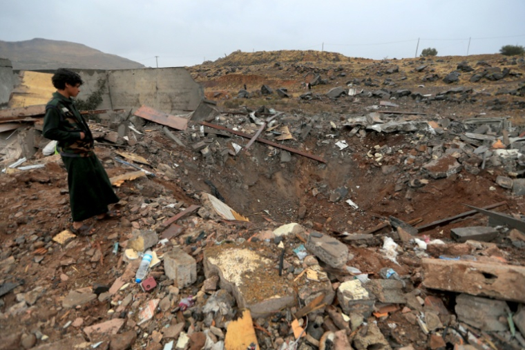 Un garçon se tient au dessus d'un cratère provoqué par une frappe attribuée à l'Arabie saoudite, qui a ciblé Sanaa, la capitale du Yémen contrôlée par les Houthis, le 24 octobre 2026 ( AFP / Mohammed HUWAIS )