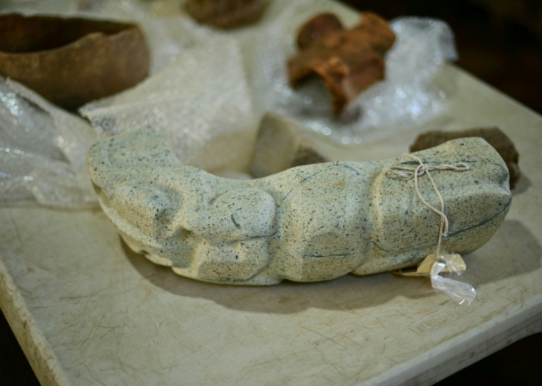 Un "joug"en pierre verte représentant un batracien figure parmi les objets découverts sur un site archéologique à Coatepec, au Mexique, le 18 juin 2026 ( AFP / Marco Antonio MARTINEZ )