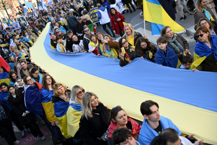 Des manifestants brandissent un drapeau ukrainien géant lors d'une marche pour l'Ukraine à Paris, à l'approche du quatrième anniversaire de l'invasion russe, le 21 février 2026 ( AFP / Bertrand GUAY )