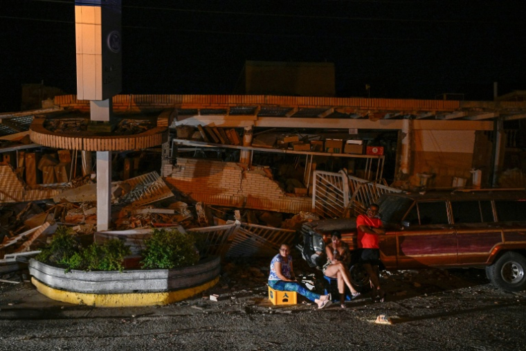 Des habitants sont assis devant des immeubles effondrés après un séisme historique Catia La Mar, le 25 juin 2026.  ( AFP / Federico PARRA )