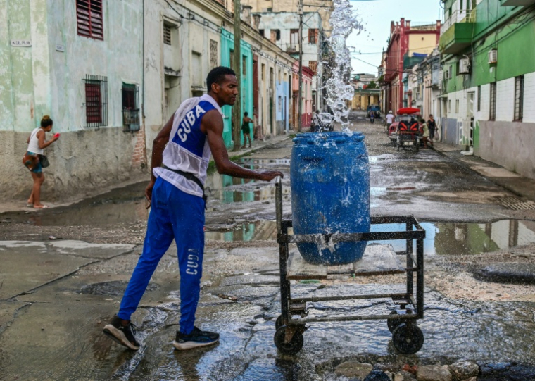 Un homme collecte de l'eau potable à un point de ravitaillement public dans une rue de La Havane, le 6 octobre 2026 ( AFP / YAMIL LAGE )
