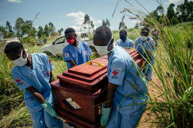 Des membres d'une équipe de la Croix-Rouge congolaise transportent le cercueil d'une femme qui serait décédée des suites de la maladie à virus Ebola lors de son enterrement dans les règles de sécurité dans un cimetière de Bunia, en RDC, le 7 juin 2026. ( AFP / Jospin Mwisha )