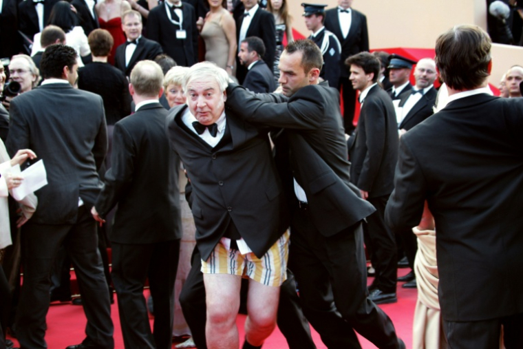 Le comique et entarteur belge Noël Godin est évacué du tapis rouge du Palais des Festivals par le service de sécurité, le 15 mai 2004, juste avant l'arrivée des célébrités pour la projection officielle de "Shrek 2" lors du Festival de Cannes ( AFP / FRANCOIS GUILLOT )