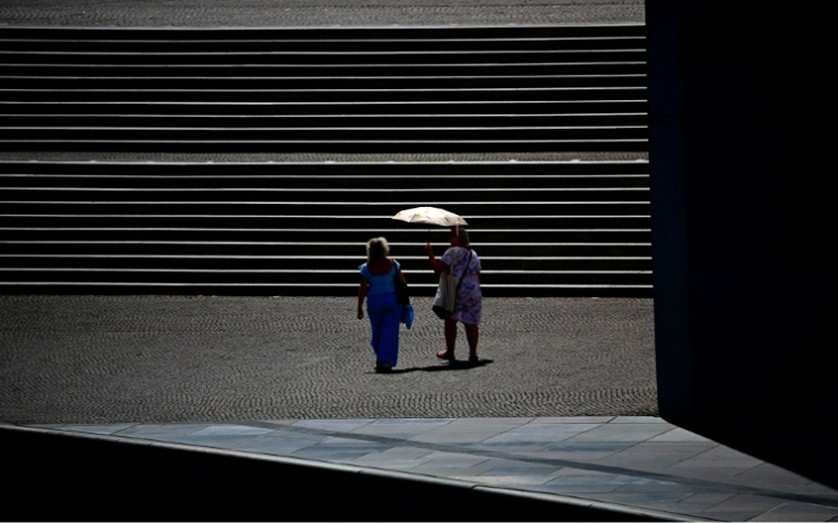 Des passantes se protègent du soleil sous une ombrelle à Berlin, pendant une vague de chlauer, le 26 juin 2026 ( AFP / Tobias SCHWARZ )
