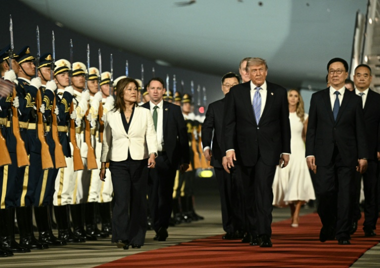 Le président américain Donald Trump (c) accompagné par le vice-président chinois Han Zheng (d) passe en revue la garde d'honneur à son arrivée à l'aéroport international de Pékin, le 13 mai 2026 ( AFP / Brendan SMIALOWSKI )