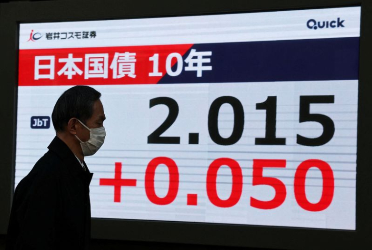 Un homme devant un écran affichant le niveau des obligations d'État japonaises à 10 ans après que la Banque du Japon a annoncé une hausse des taux d'intérêt à Tokyo