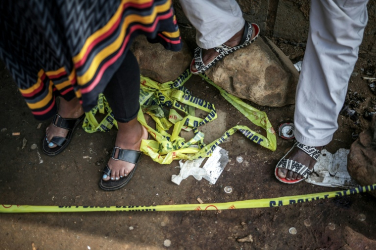 Des habitants derrière un cordon policier près du lieu de la fusillade dans un bar de l'ouest de Johannesburg qui a fait 17 morts et 15 blessés, le 27 septembre 2026   ( AFP / EMMANUEL CROSET )