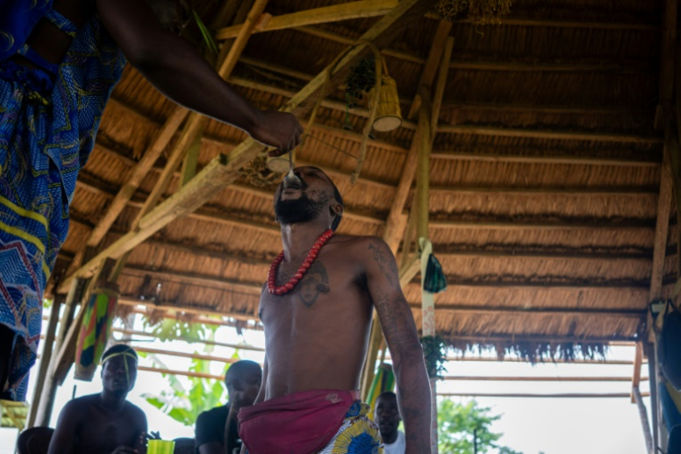 Un initié consomme une cuillérée de poudre d'iboga lors d'une cérémonie bwiti au village de Ndossi, à Akanda, le 13 février 2025 au Gabon ( AFP / Nao Mukadi )