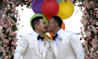 Les Chinois Song Jihan (g) et Wang Zengyi s'embrassent lors de la cérémonie de leur mariage près de Pattaya, dans la province de Chonburi, le 31 mai 2025 en Thaïlande ( AFP / Lillian SUWANRUMPHA )